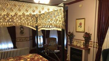 A traditional room with a four-poster bed, a fireplace, and floral decorations.