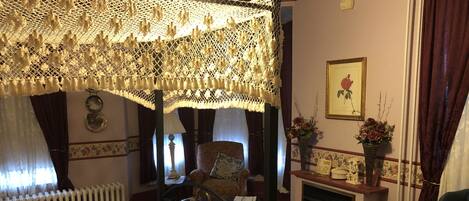Habitació tradicional amb un llit baldaquí, una llar de foc i decoracions florals.