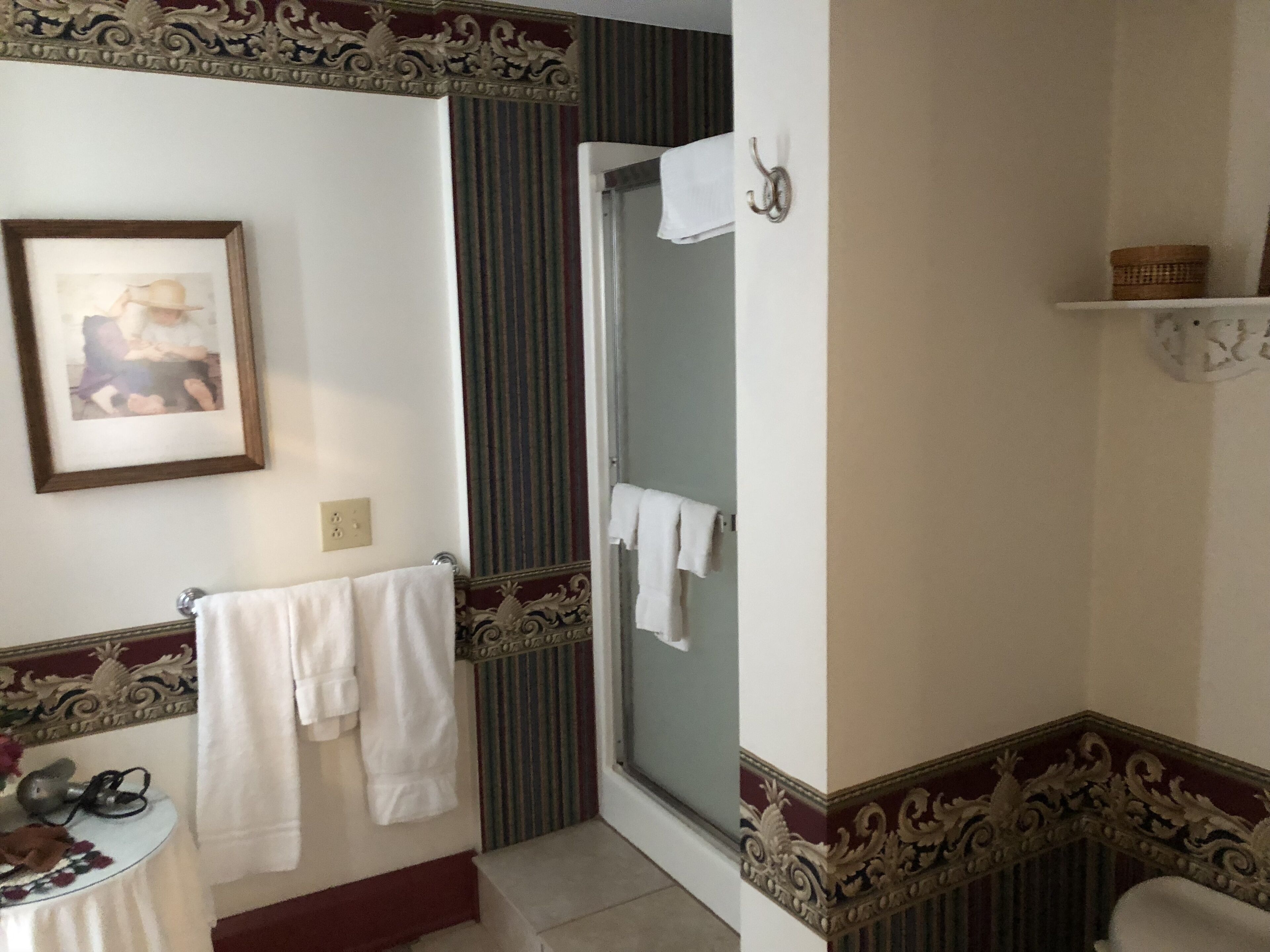 A bathroom with a framed picture, a towel rack, a sink, and a shower area.