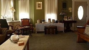 A traditional living room with a fireplace, a dining table, and a sofa. - Keller House (Centre Hall)
