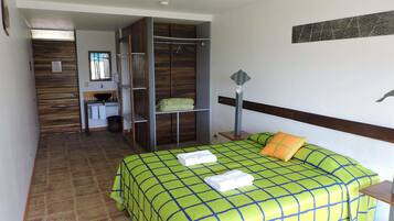 Un dormitorio con cama, mesita de noche, armario, espejo y baño con lavamanos e inodoro.