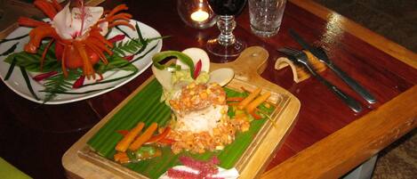 A dining table with a variety of dishes, including a plate with a fish dish, a plate with a vegetable dish, and a glass of red wine.