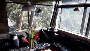 A modern interior with a leather sofa, a wooden table, and a vase with plants. - Celeste Mountain Lodge (Bijagua)