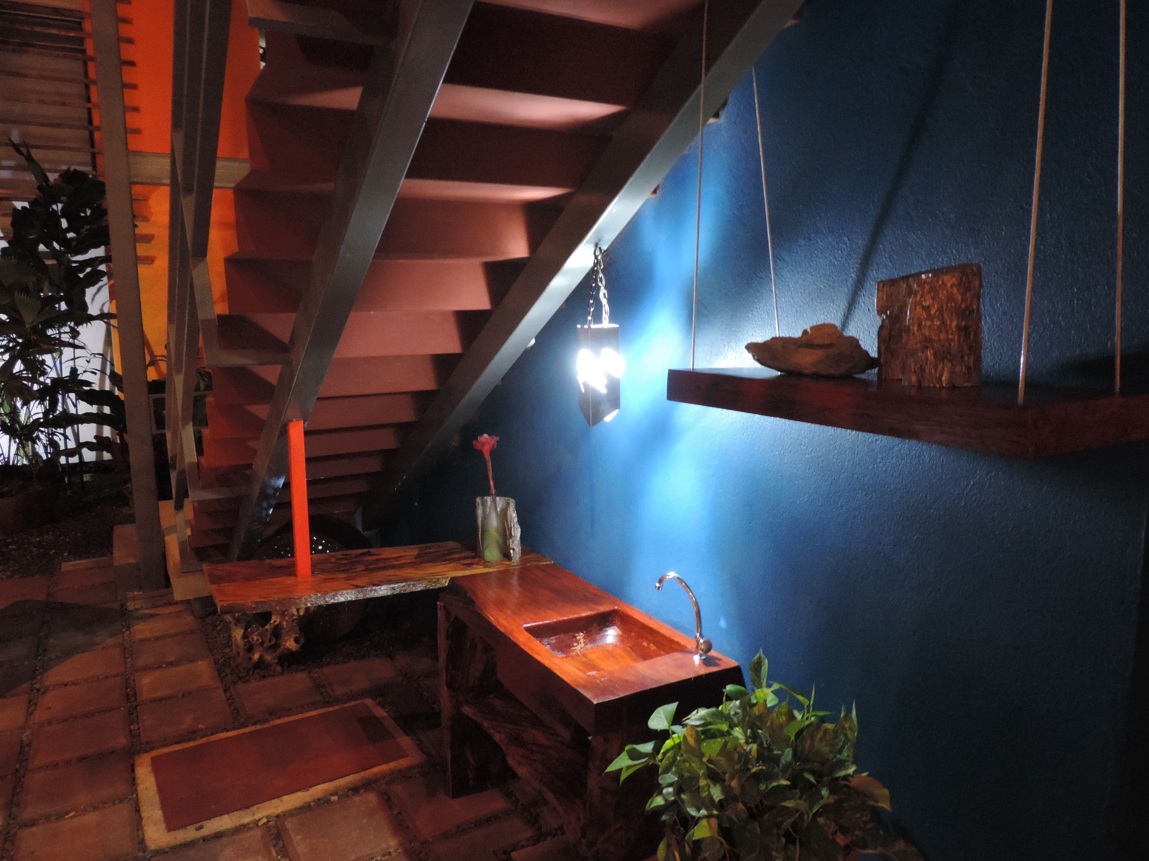 Een houten trap met een blauwe muur en een hanglamp.