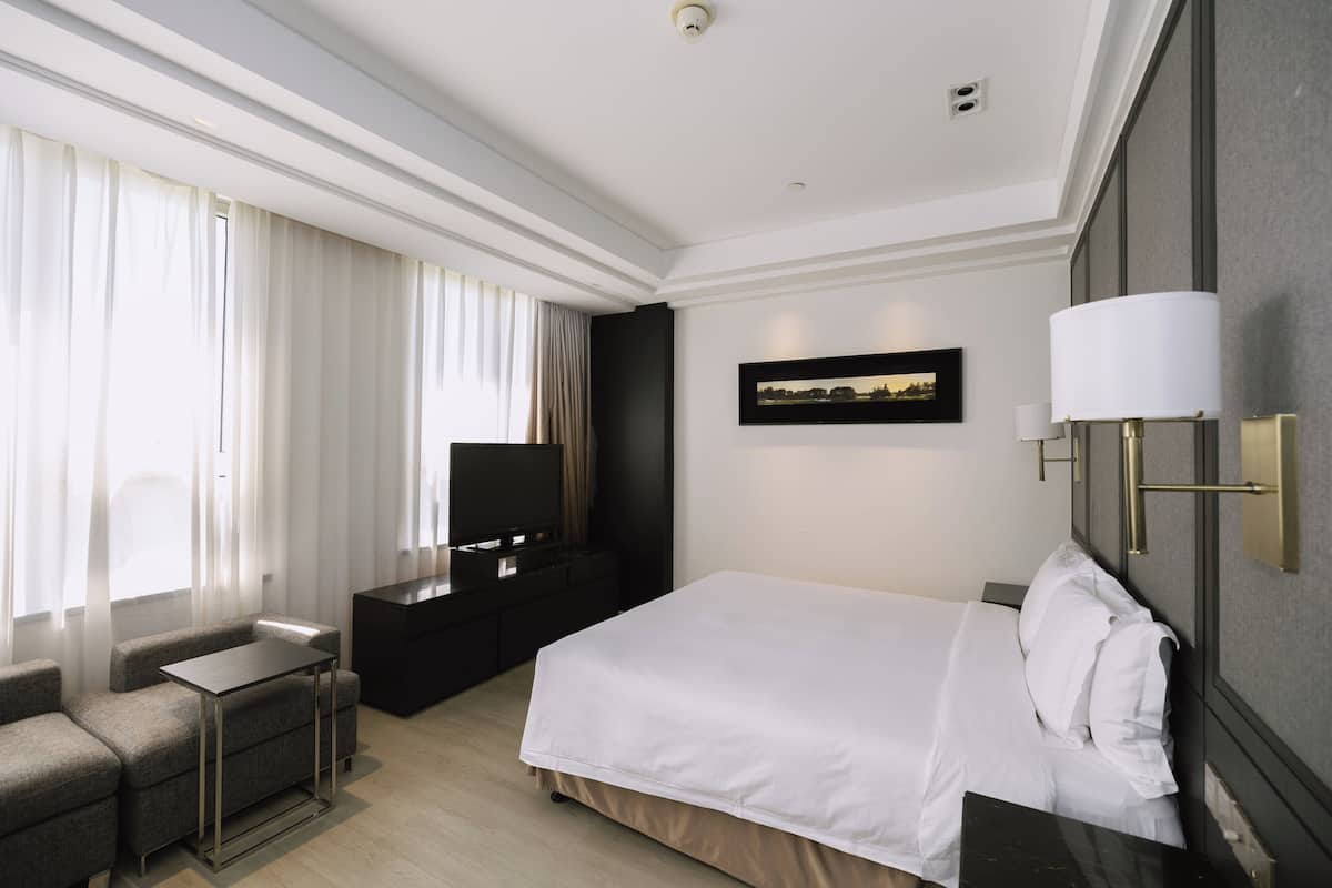 Habitació d'hotel amb llit, televisió, escriptori i sofà.