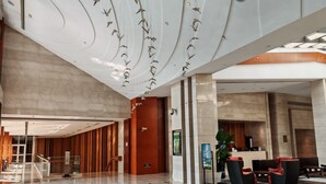 Un vestíbulo amplio con diseño moderno, que cuenta con un mostrador de recepción, zona de estar y una escalera.