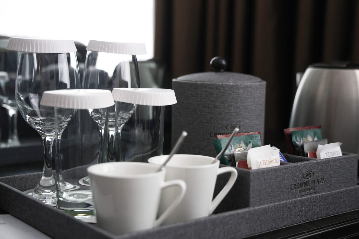 A tray with a coffee maker, cups, and a glass.