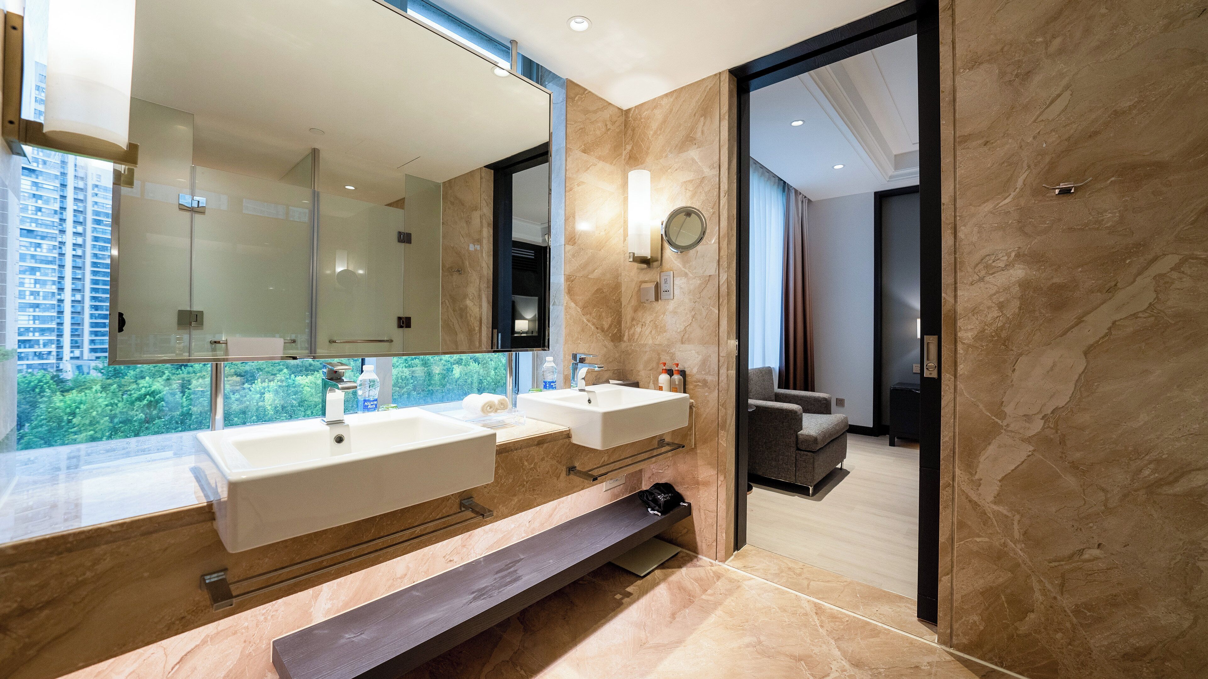 Un baño moderno con lavamanos dobles, un espejo grande y vistas al exterior.