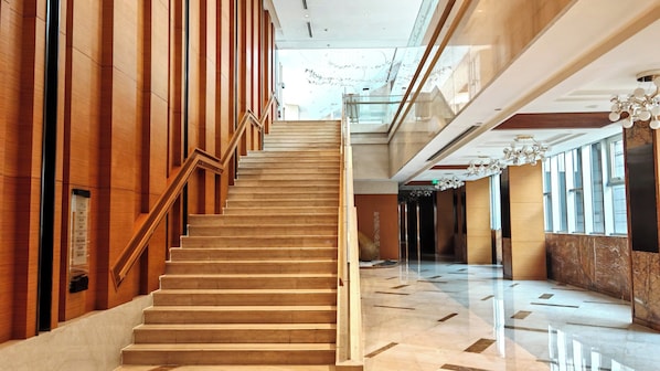 A modern hotel lobby with a wooden staircase, marble flooring, and large windows. - Crowne Plaza Shanghai Anting - 20 Minutes drive to National Exhibition and Convention Center & 15 Minutes drive to F1 (Shanghai)