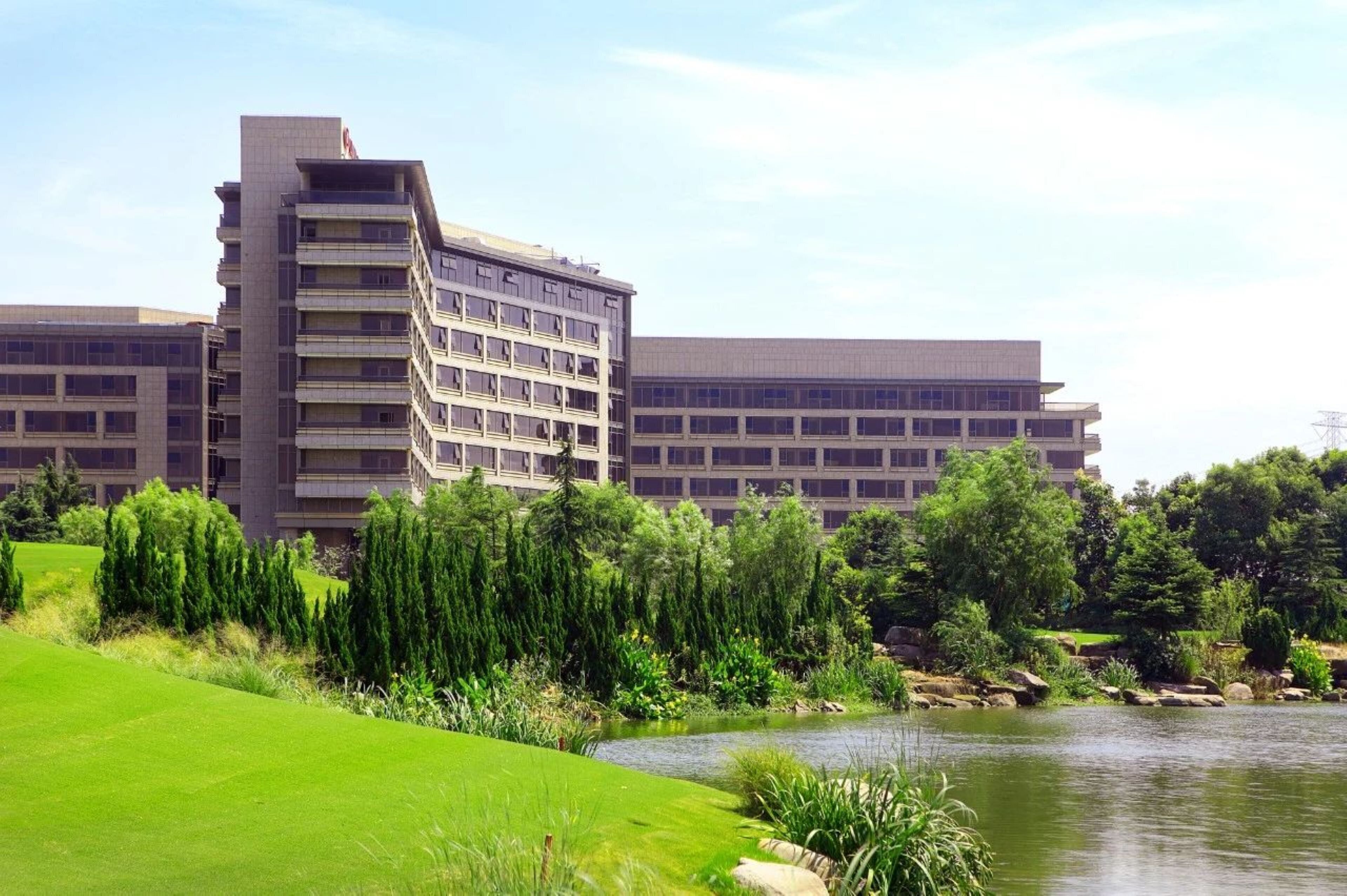 A multi-story hotel with a flat roof and a large parking lot.