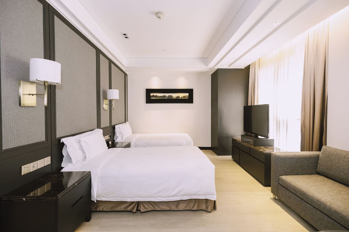 Una habitació d'hotel amb un llit, un sofà, una televisió i un quadre al mur.