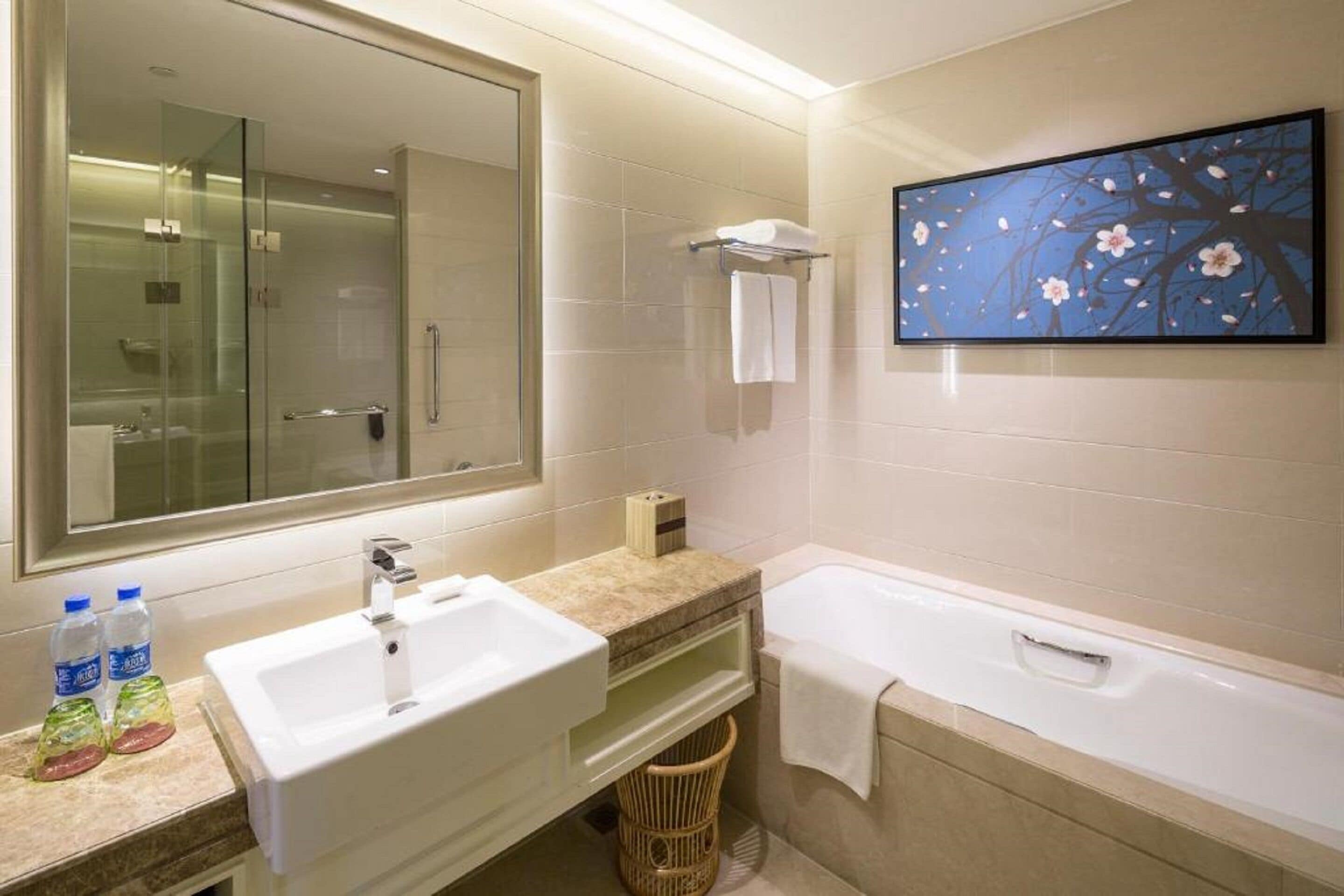 A modern bathroom with a large mirror, a sink, a bathtub, and a wall-mounted TV.