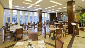A spacious restaurant with multiple tables and chairs, large windows, and a central pillar. - Eurobuilding Express Barinas (Barinas)