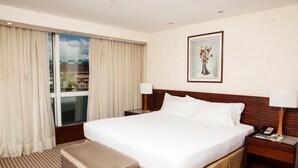 A hotel room with a large bed, a bedside table with a lamp, a window with curtains, and a framed picture on the wall. - Eurobuilding Express Barinas (Barinas)