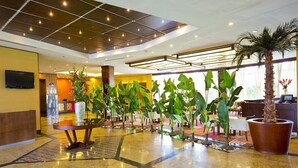 A hotel lobby with a tiled ceiling, a reception desk, and a row of potted plants. - Eurobuilding Express Barinas (Barinas)