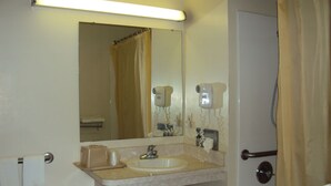 A bathroom with a sink, mirror, hairdryer, and a small stool. - Western Motel (Folkston)