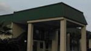 A building with a green roof and a covered entrance area. - Western Motel (Folkston)