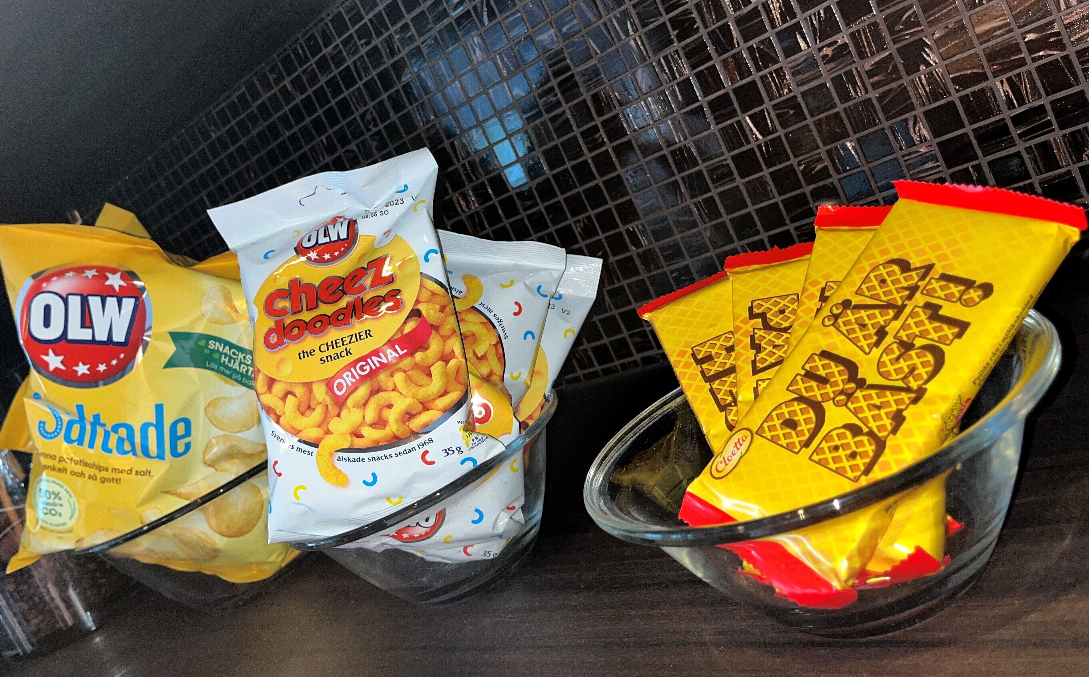 Ett urval av snacksförpackningar, inklusive OLW-snacks och Cheez Doodles, förvarade på ett och samma ställe.