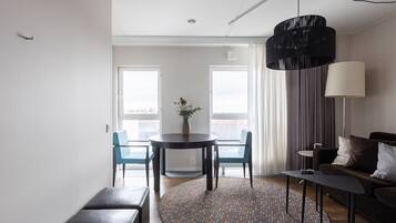 Una sala de estar moderna con una mesa redonda, dos sillas azules, un sofá oscuro y una alfombra estampada.