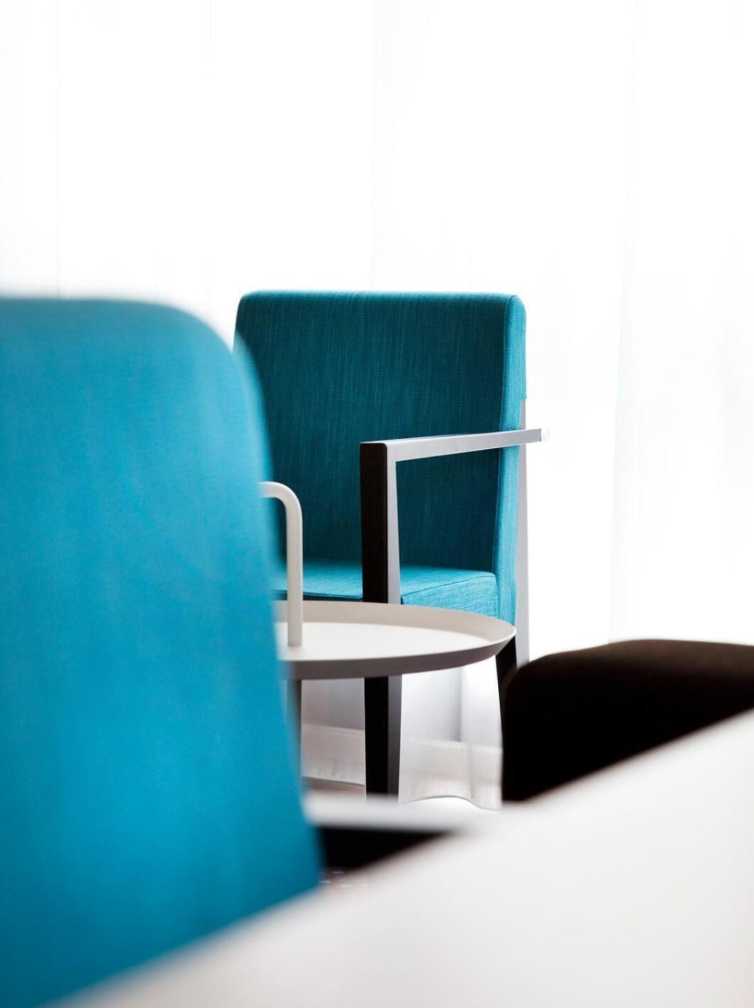 A modern room with a teal armchair and a white table.