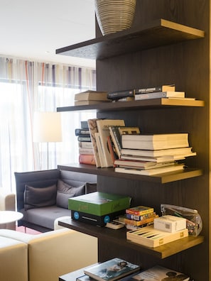 Una sala de estar moderna con una estantería de madera oscura llena de libros, una caja verde etiquetada 'Lund' y una revista sobre una mesa de centro.