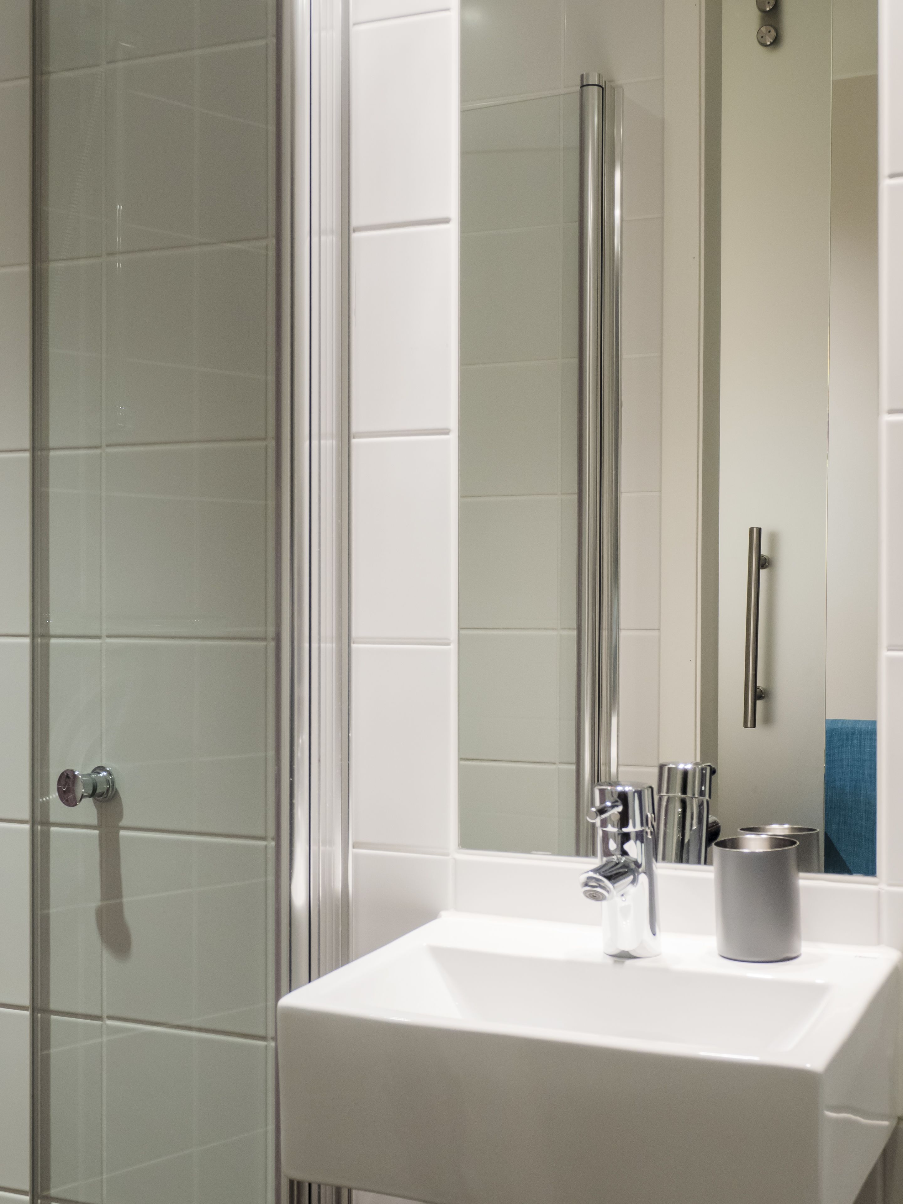 Un bagno moderno con box doccia in vetro, un lavandino bianco e uno specchio.
