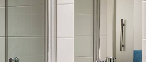 Un baño moderno con cabina de ducha de vidrio, lavamanos blanco y espejo.