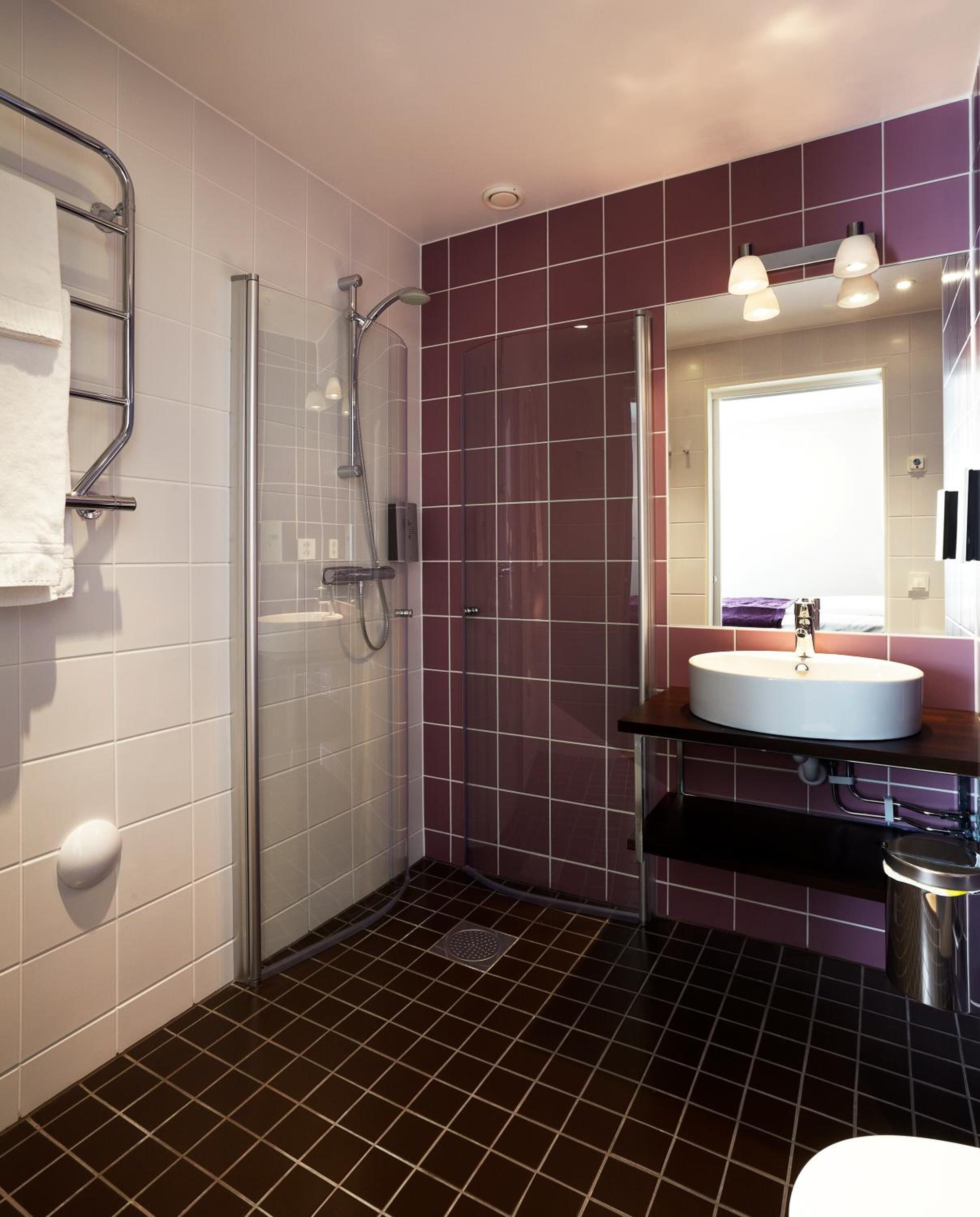 A modern bathroom with a glass-enclosed shower, a white sink, and a vanity with a mirror.