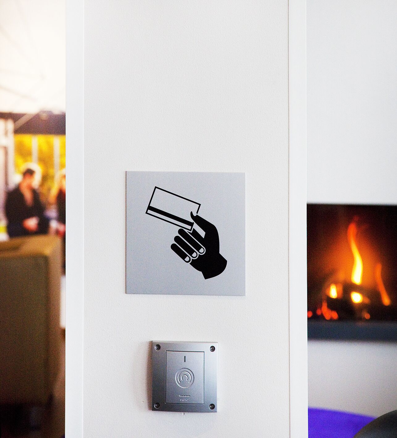 Un cartel en la pared muestra una mano sosteniendo una tarjeta de crédito, un detector de humo y una chimenea.