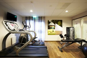 Un gimnasio con cinta de correr, banco de pesas y equipo de ejercicio.