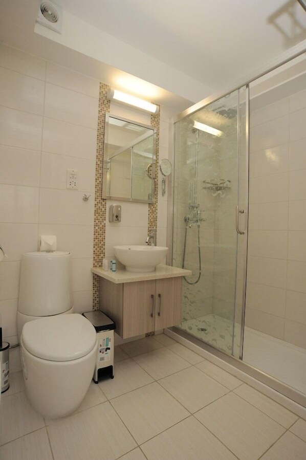 A modern bathroom with a toilet, sink, and glass shower enclosure.