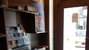 A bookstore with shelves stocked with books and magazines, a 'Book Here' sign, and a 'No Smoking' sign on the door. - Blossom Guest House (Edinburgh)