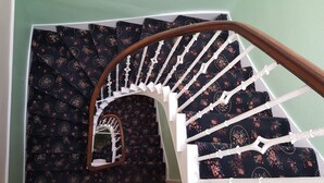 A spiral staircase with a floral-patterned carpet and white balusters. - Blossom Guest House (Edinburgh)