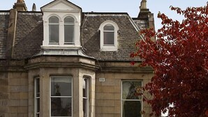 A corner building with a 'Vacancies' sign, a 'Guest House' sign, and a parked car in front. - Blossom Guest House (Edinburgh)