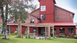 A red brick building with a covered patio area, large windows, and a small garden. - Kvibergs Vandrarhem - Hostel (Gothenburg)