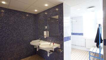 Een badkamer met twee wastafels, een spiegel en een bankje.