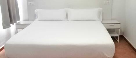 A standard hotel room with a large bed, a nightstand, and a headboard.