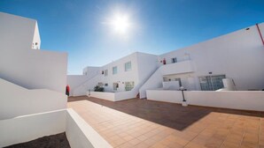 A modern building with white walls and a tiled courtyard. - Tabaiba Apartamentos (Teguise)