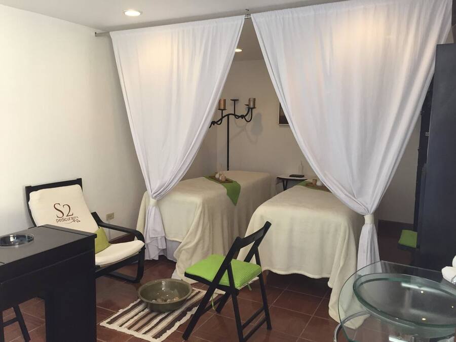 Ein Zimmer mit zwei Betten, die mit weißen Vorhängen drapiert sind, einem kleinen Tisch mit einer Schale, einem Stuhl und einem Glastisch.