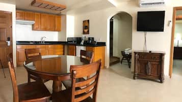 Una cocina moderna con armarios de madera, una mesa de comedor con sillas, una isla integrada y un televisor de pantalla plana montado en la pared.