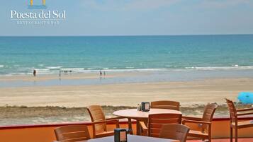 Een restaurant aan het strand met terras en uitzicht op de oceaan.