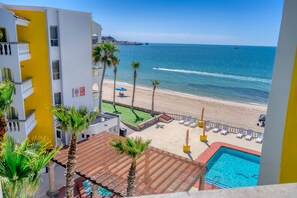A hotel with a pool, beach view, palm trees, and a beach with lounge chairs. - Playa Bonita (Puerto Peñasco)