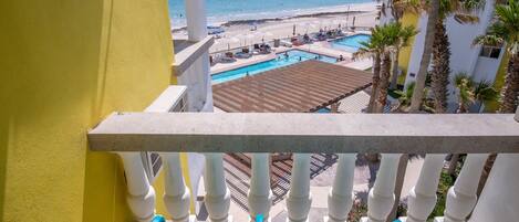 A balcony with a view of a beach and a pool.