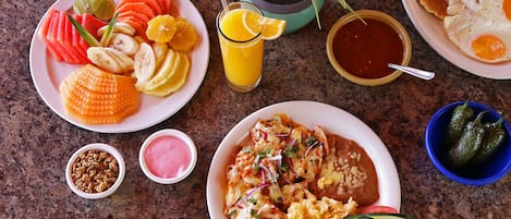 A breakfast spread with various dishes and drinks on a granite countertop.