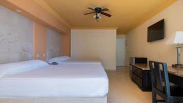 A hotel room with two beds, a ceiling fan, a television mounted on the wall, and a desk with a chair.