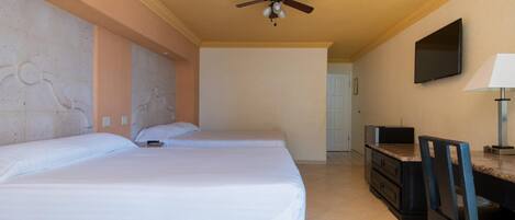 A hotel room with two beds, a ceiling fan, a television mounted on the wall, and a desk with a chair.