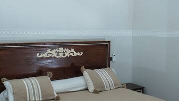 A hotel room with a bed, a nightstand, and a wall-mounted air conditioner.
