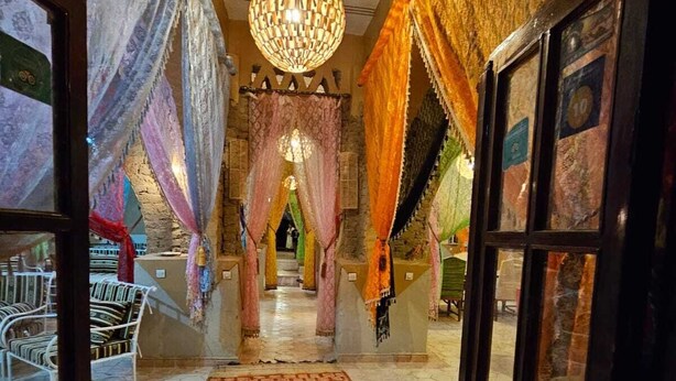 A hallway with a patterned carpet, a chandelier, and draped fabric on the walls.