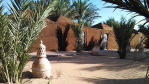 A desert landscape with palm trees and traditional tents.