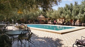 Una piscina al aire libre, sombrillas, sillones reclinables de piscina